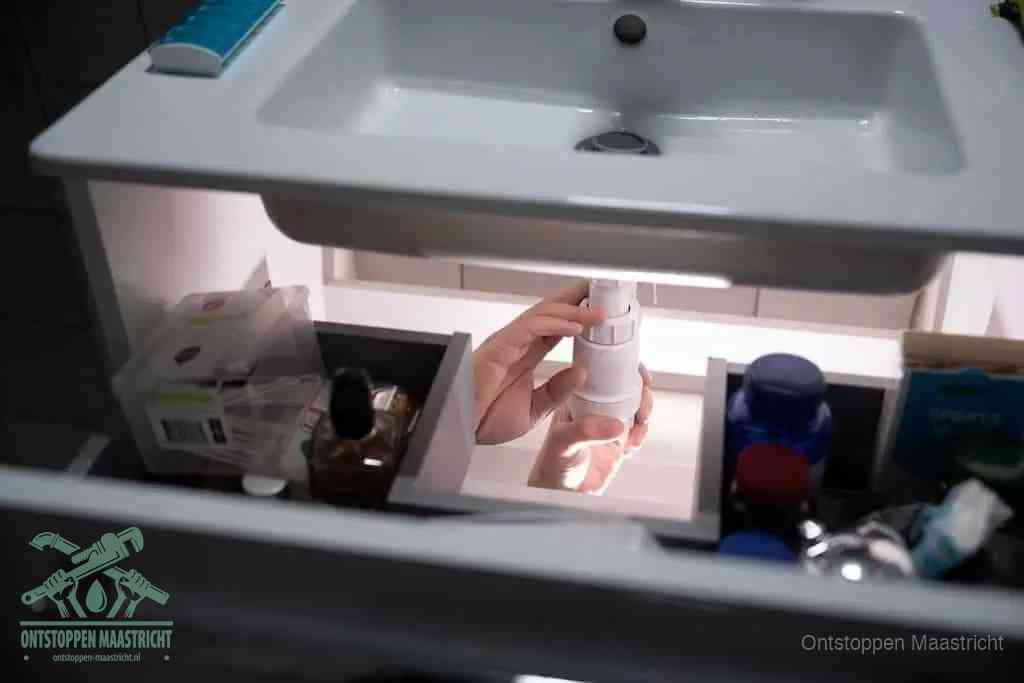 Een pompfles met zeep boven een wastafel, de heet water en afwasmiddel-methode om een vetprop in de afvoer los te maken in Maastricht