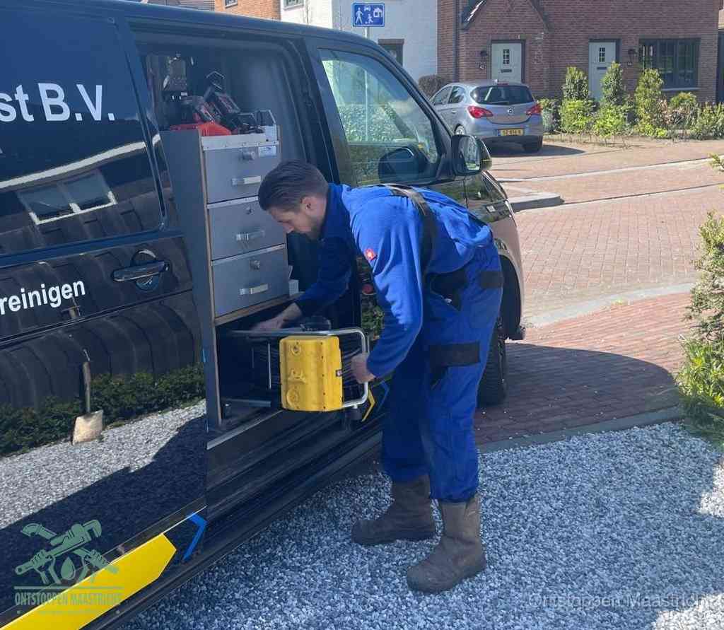 Een monteur pakt buiten op de oprit gereedschap uit de bedrijfsbus, het moment om een professional in te schakelen voor een verstopte afvoer in Maastricht