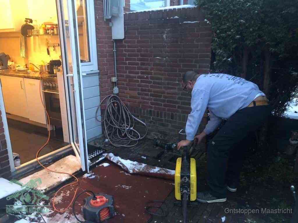 Een monteur werkt buiten bij een open riool-/grondput met een elektrische ontstoppingsmachine om een verborgen afvoerprobleem op te sporen in Maastricht