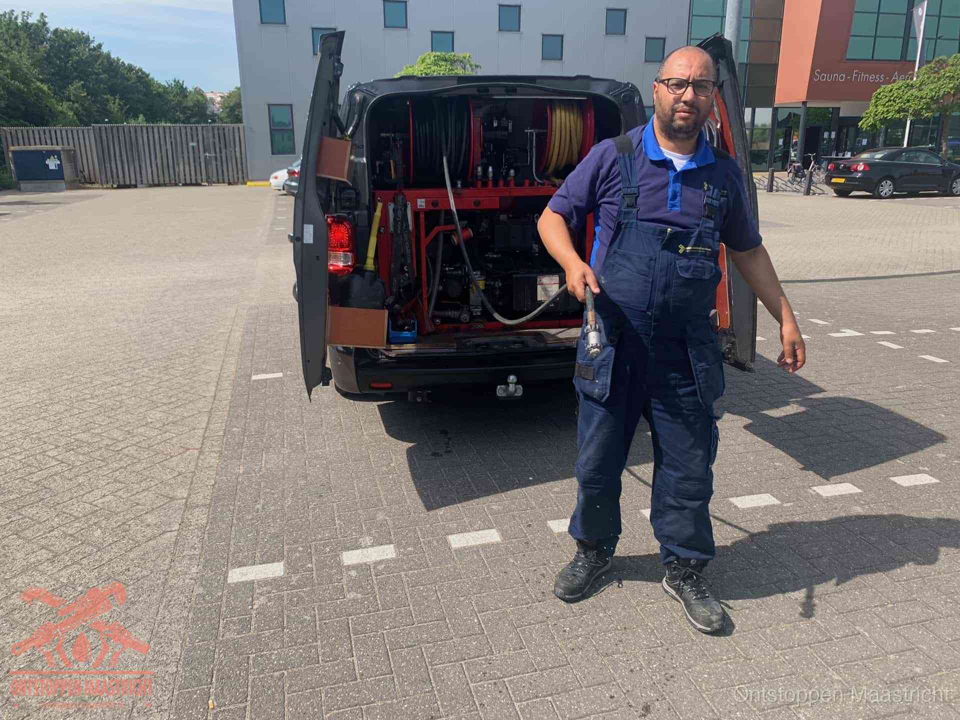 Een monteur bij zijn bestelbus met een hogedruk- en rioolreinigingsunit, klaar om de oorzaak van terugkerende wc-verstoppingen aan te pakken in Maastricht