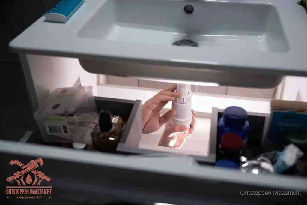 Een pompfles met zeep boven een wastafel in de toiletruimte, de warm water en afwasmiddel-methode om de wc te ontstoppen in Maastricht