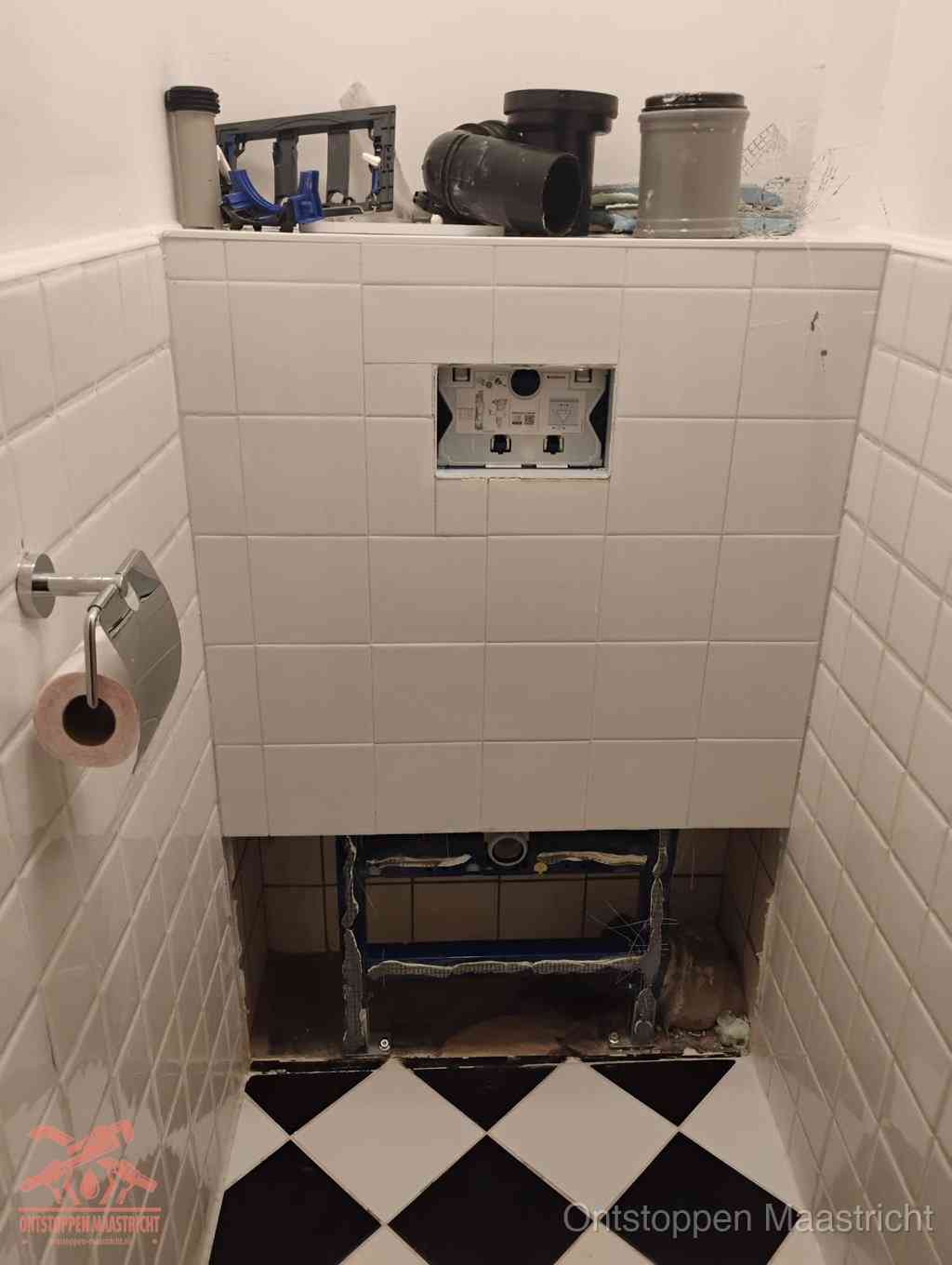 Een toiletruimte waar het hangtoilet en de inbouwreservoir-onderdelen zijn vrijgelegd voor onderhoud, periodiek nazicht voorkomt een wc-verstopping in Maastricht